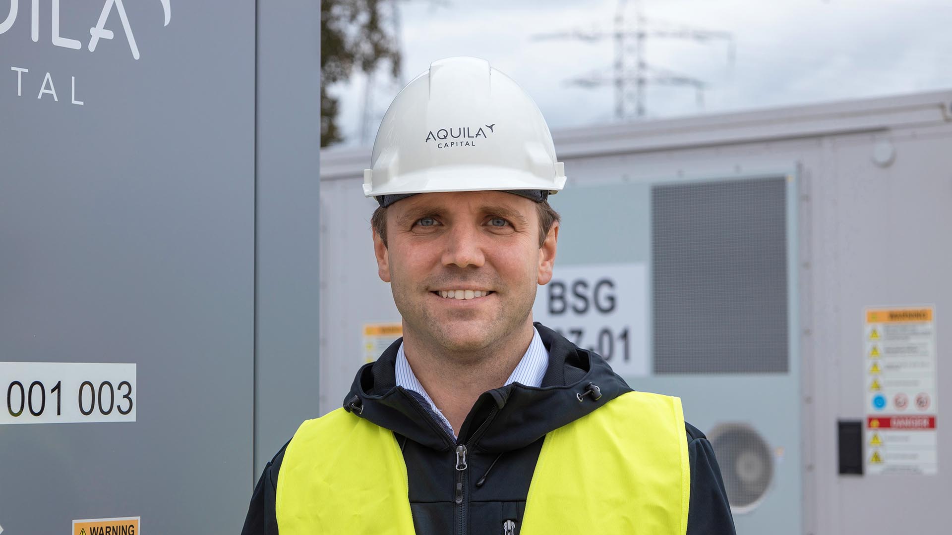 Aquila Clean Energy Crew member standing at the Kairos battery energy storage system (BESS)