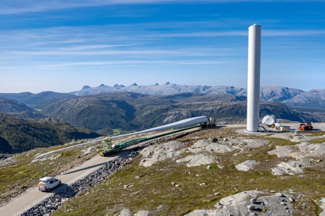 Wind turbine under construction in the mountains and rotor blade transported by truck.